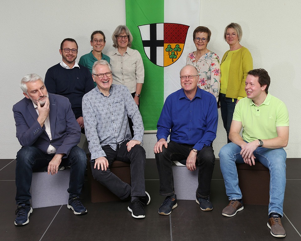 Gruppenfoto von Team Kell, den Kandidatinnen und Kandidaten für den Ortsbeirat. Vier Frauen und fünf Männer vor einer Fahne mit dem Wappen von Andernach-Kell.